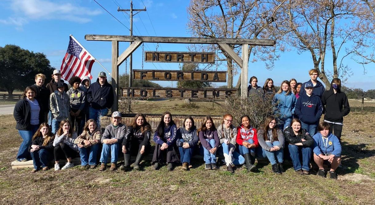 a group of people are posing for a picture in front of a sign .