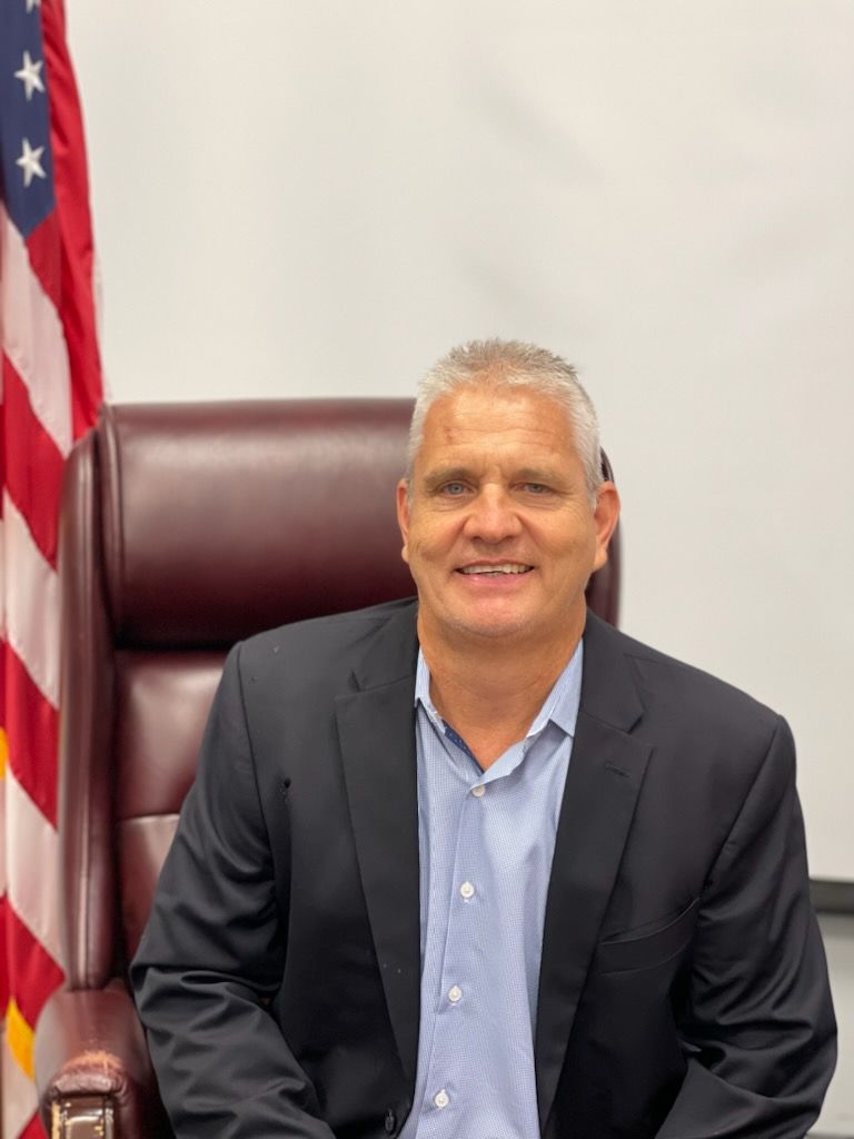 a man in a suit is sitting in a chair in front of an american flag .