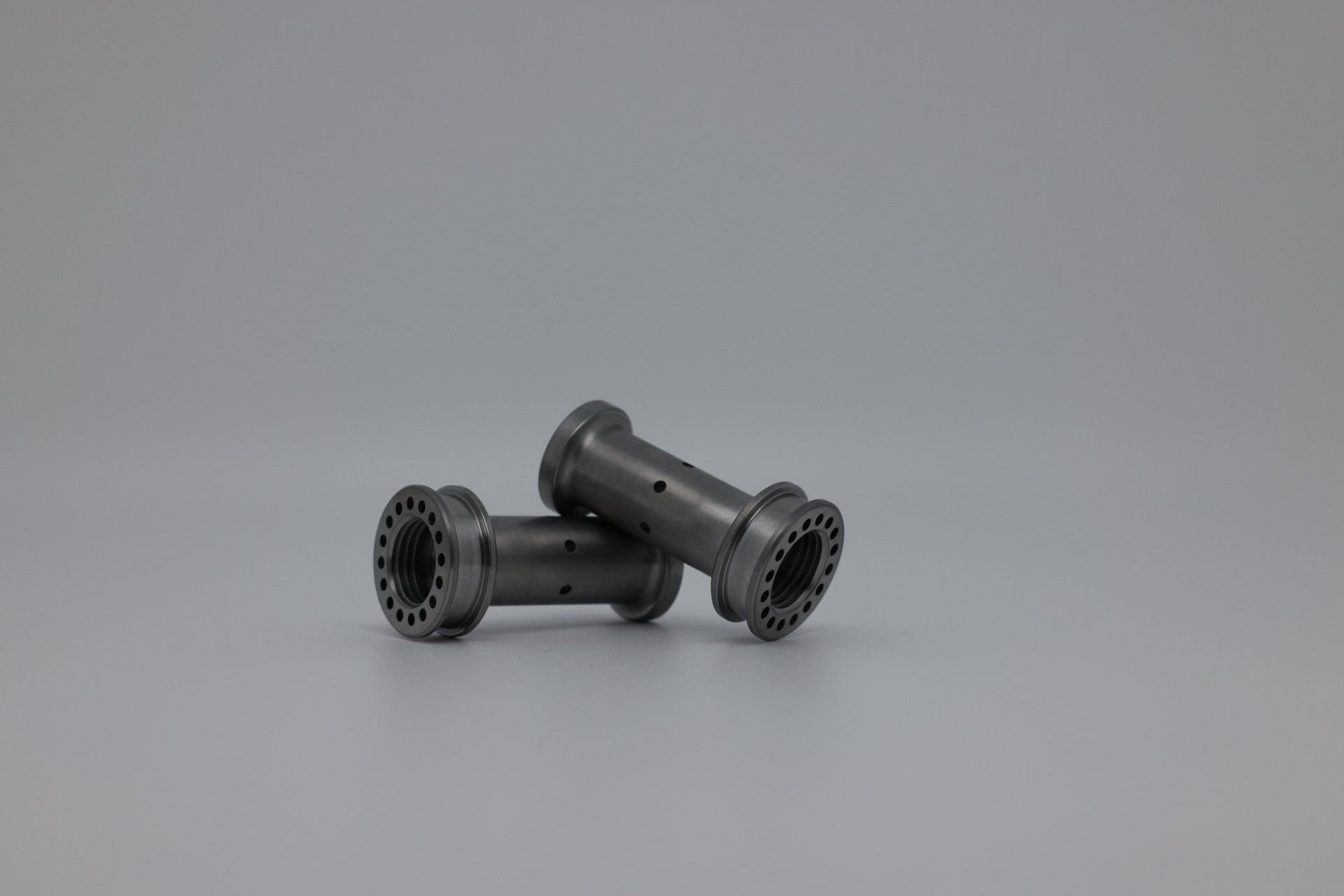 Two metal spools are stacked on top of each other on a gray surface.