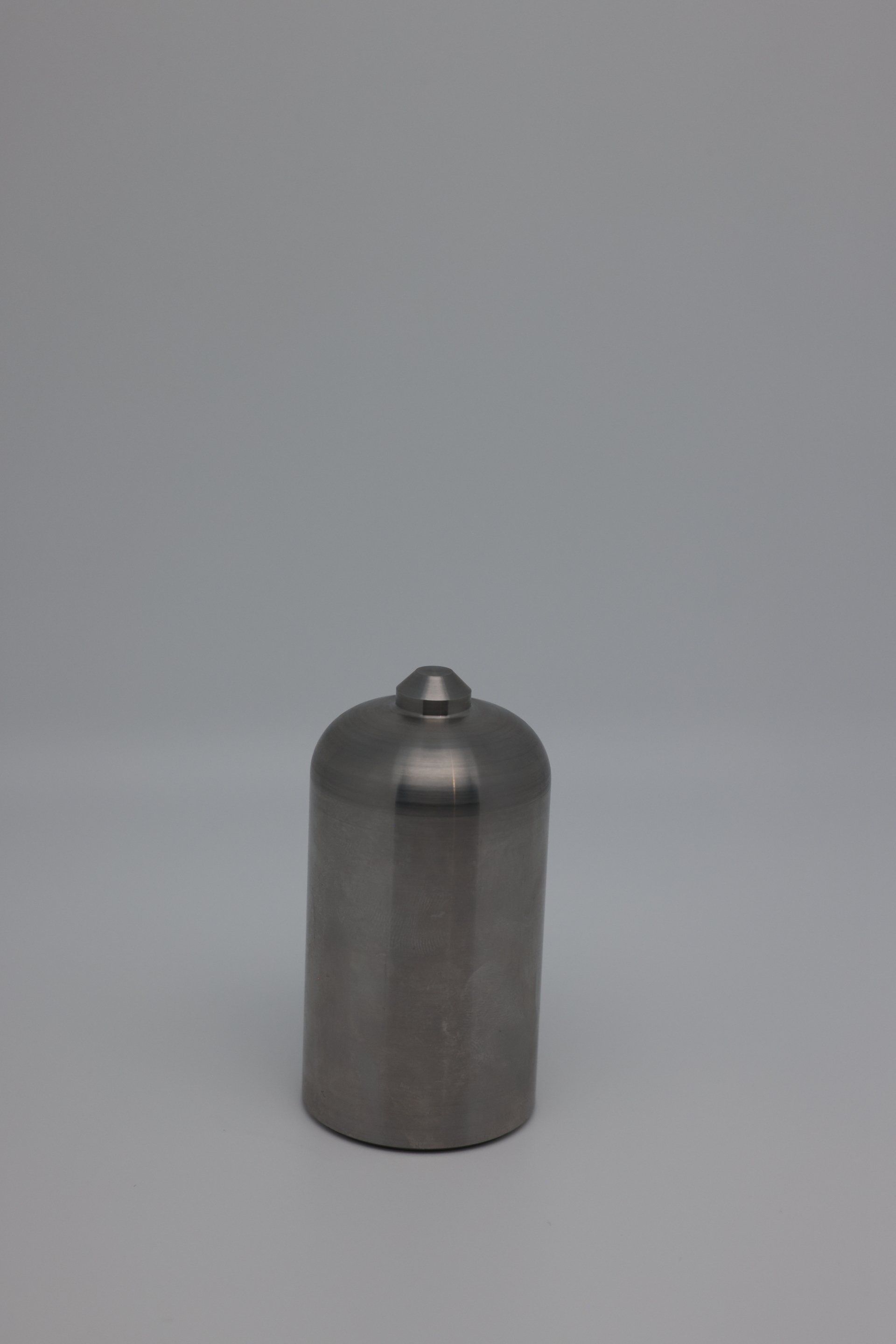 A small stainless steel object is sitting on a white surface.