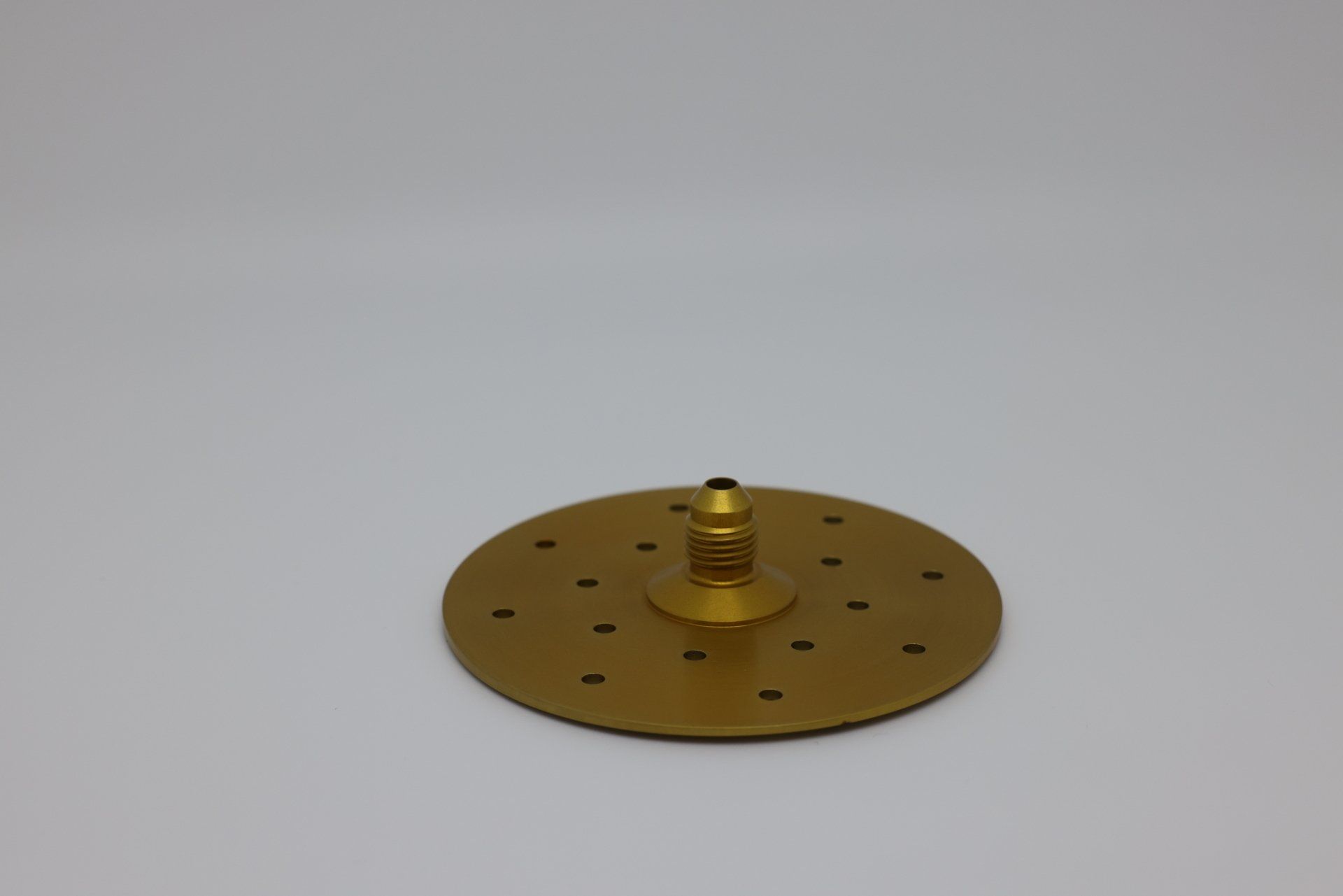 A gold plate with a spring on top of it on a white surface.