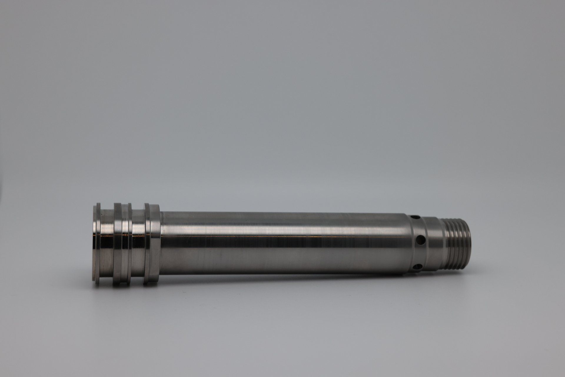 A stainless steel shaft is sitting on a white surface.