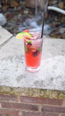 Pink drink with lime wedge and straw on a concrete ledge outdoors