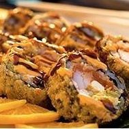 Sauced fried sushi rolls on a plate, drizzled with dark sauce and topped with green garnish