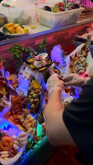 Person serving assorted colorful desserts at a brightly lit dessert buffet counter