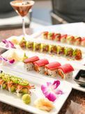 Colorful sushi platter on tiered trays with a cocktail glass on a table