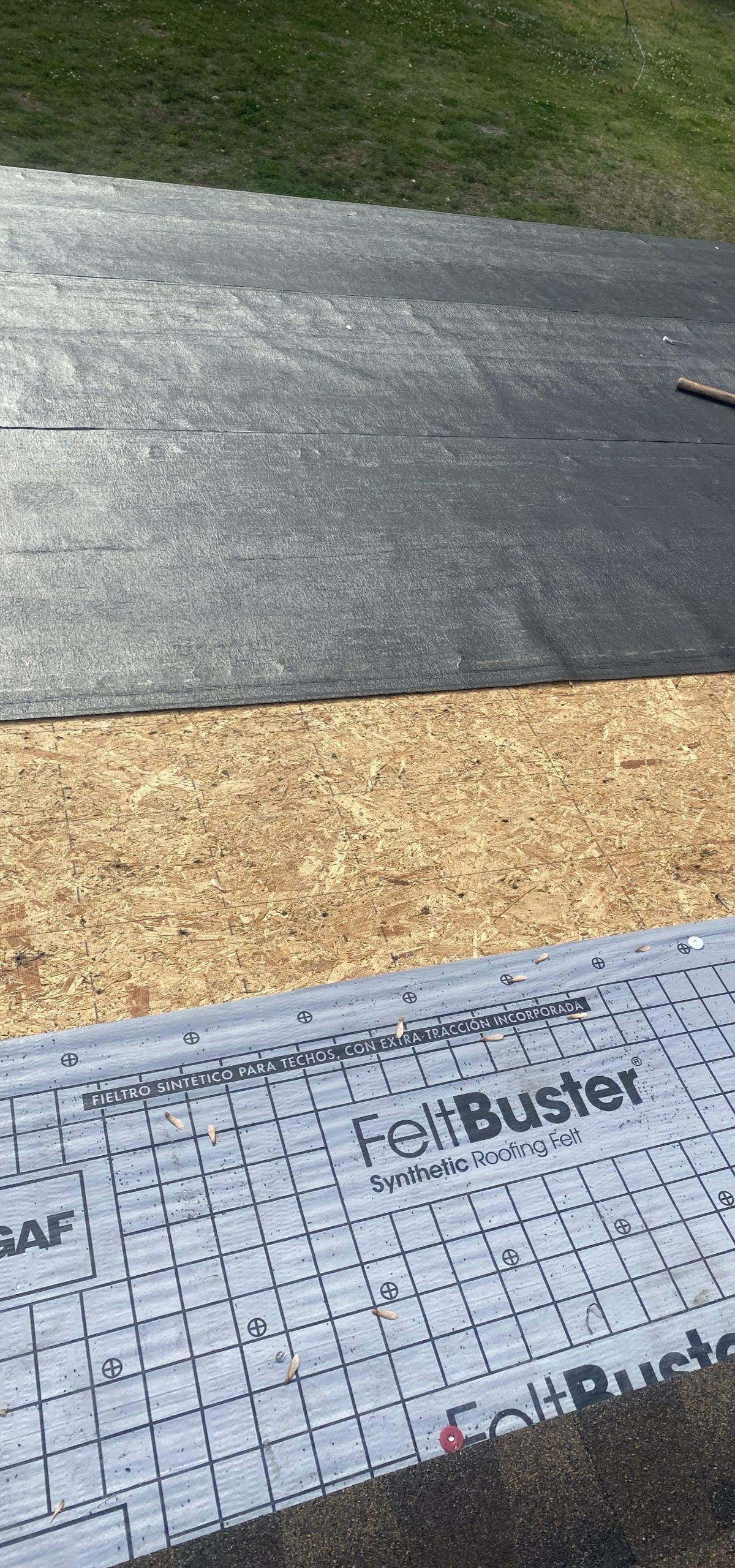 GAF FeltBuster synthetic underlayment installed over wooden roof decking, with a section of black roofing felt above.