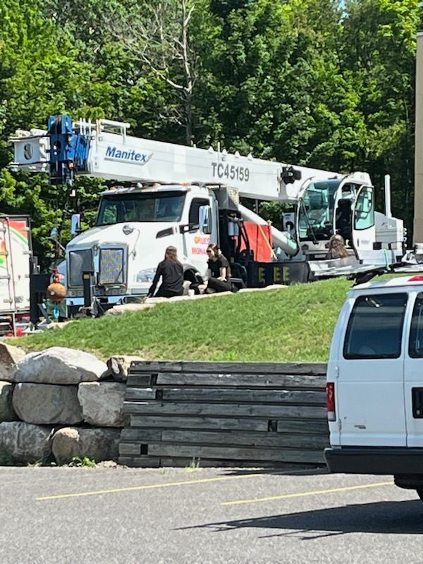 Un camion surmonté d’une grue est garé dans un parking.
