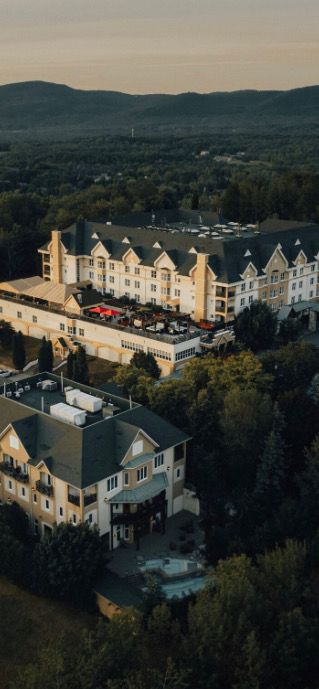 Une vue aérienne d un grand hôtel entouré d arbres et de montagnes.