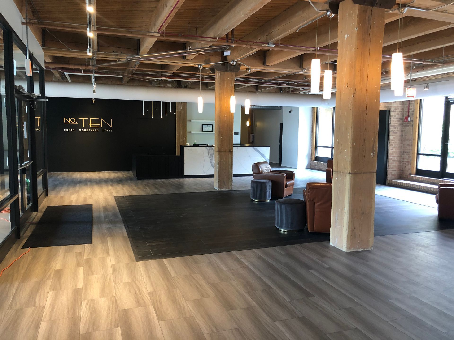 Spacious modern lobby with wood floors, exposed beams, seating, and large windows