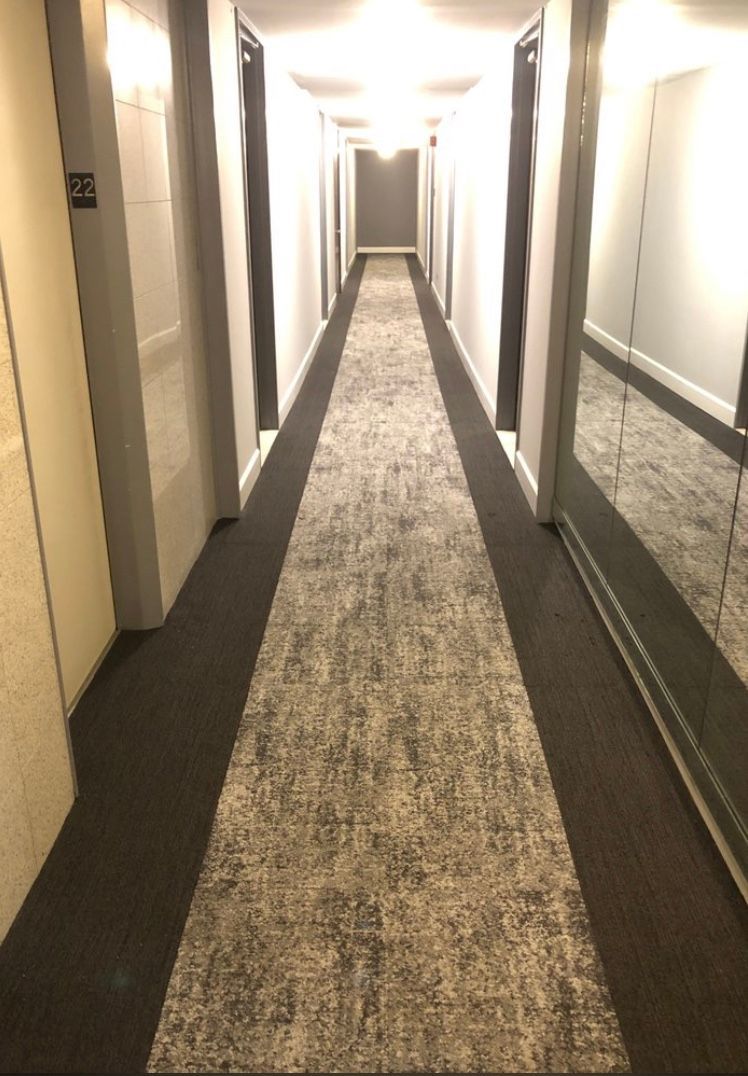A long hallway with a carpeted floor and a mirror on the wall.