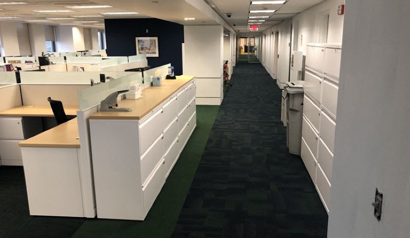A long hallway in an office with cubicles and filing cabinets