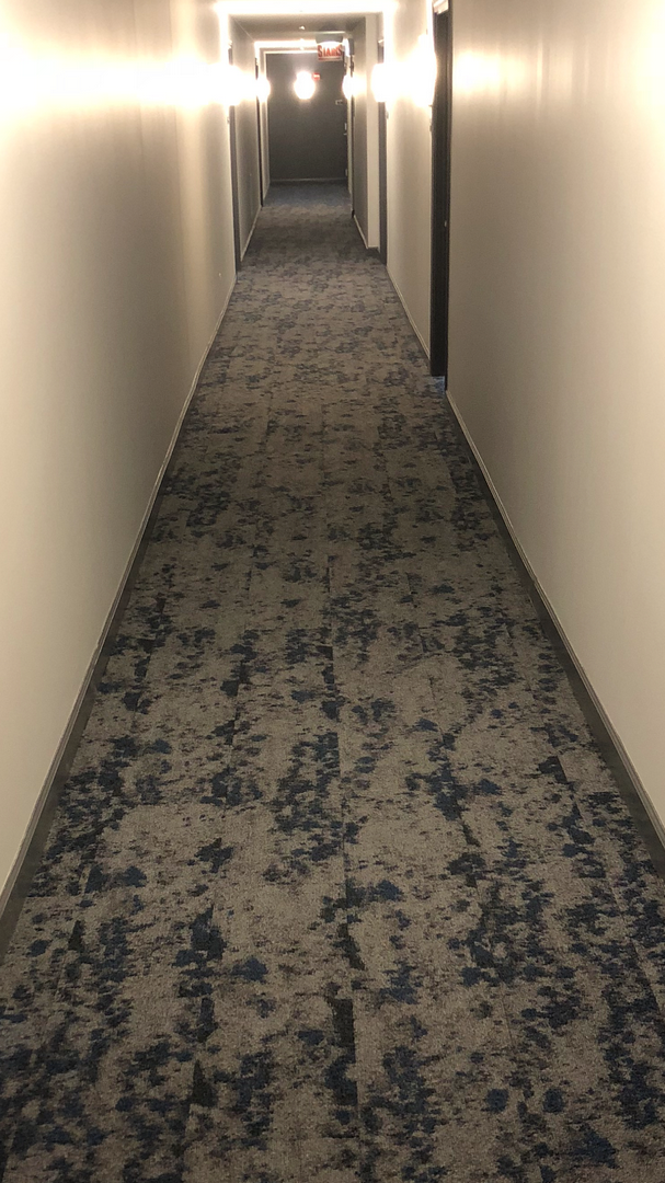 A long hallway with a carpeted floor in a hotel.