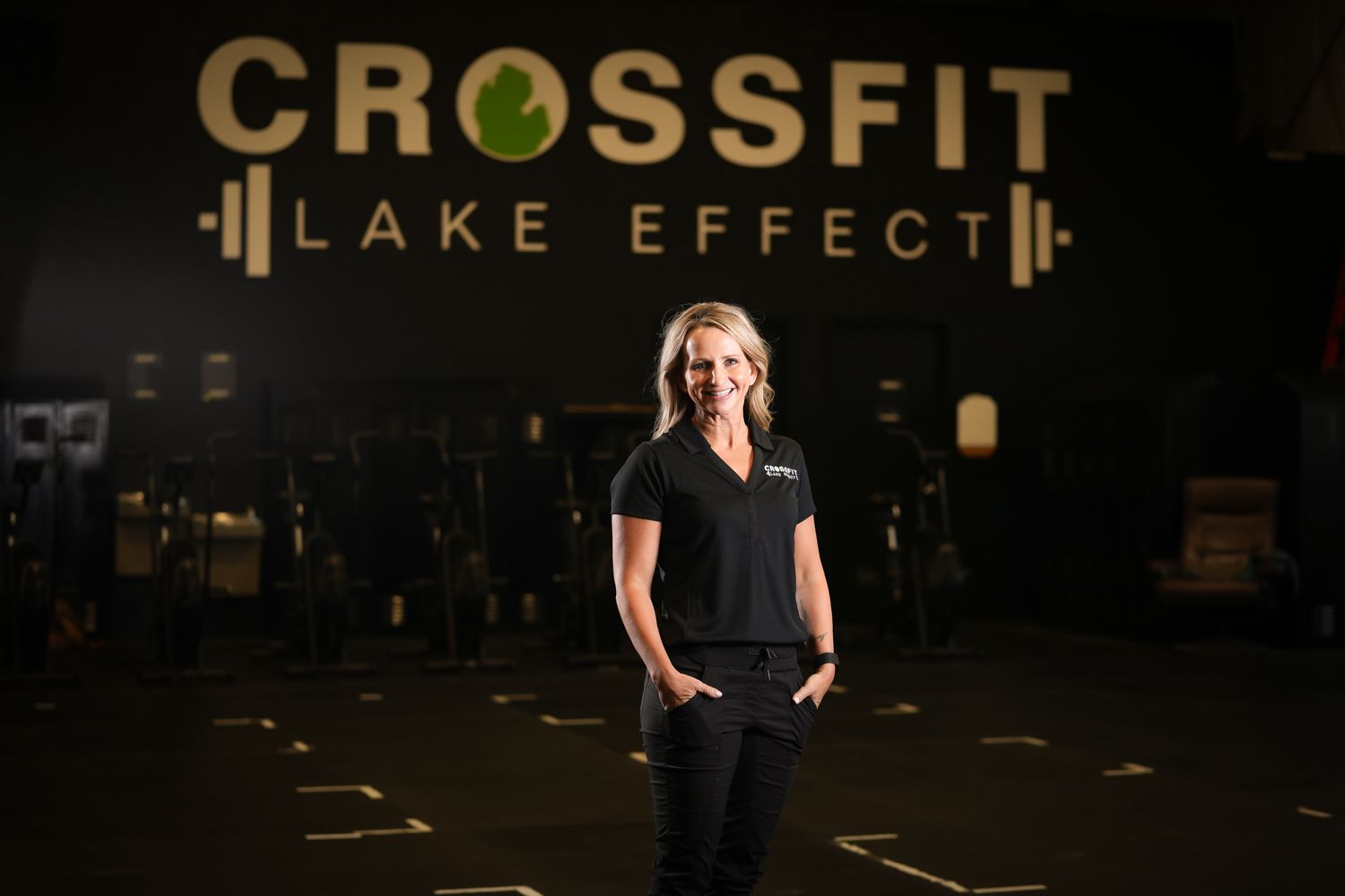 A woman is standing in front of a sign that says crossfit lake effect