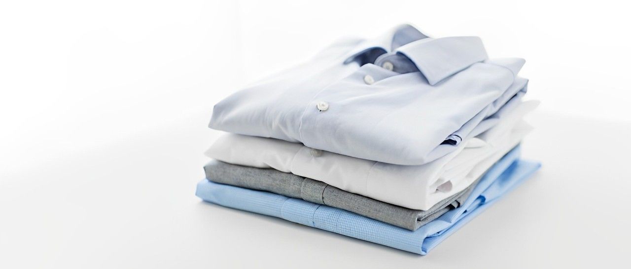 A Stack Of Folded Shirts And Sweaters On A White Surface — Macquarie Dry Cleaners In Dubbo, NSW