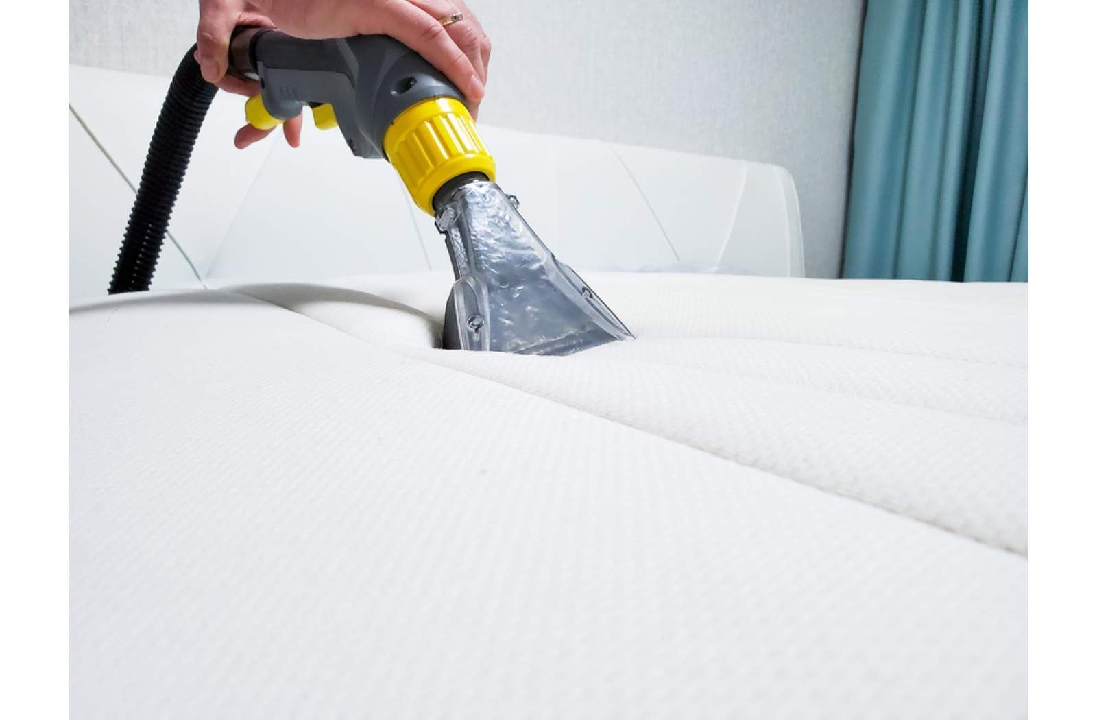 A Person Is Cleaning A White Couch With A Vacuum Cleaner — Macquarie Dry Cleaners In Dubbo, NSW