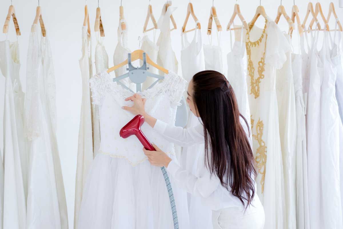 A Woman Is Blow Drying A Wedding Dress In A Store — Macquarie Dry Cleaners In Dubbo, NSW