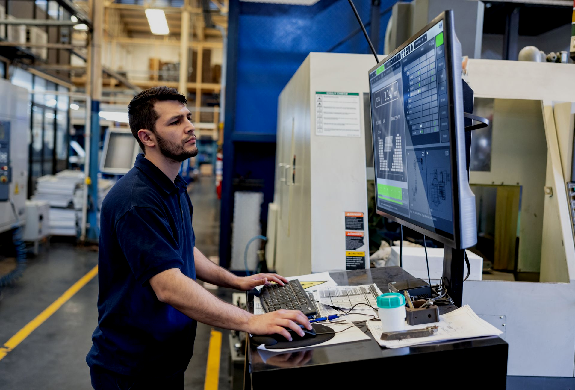 man in a manufacturing environment working on a computer