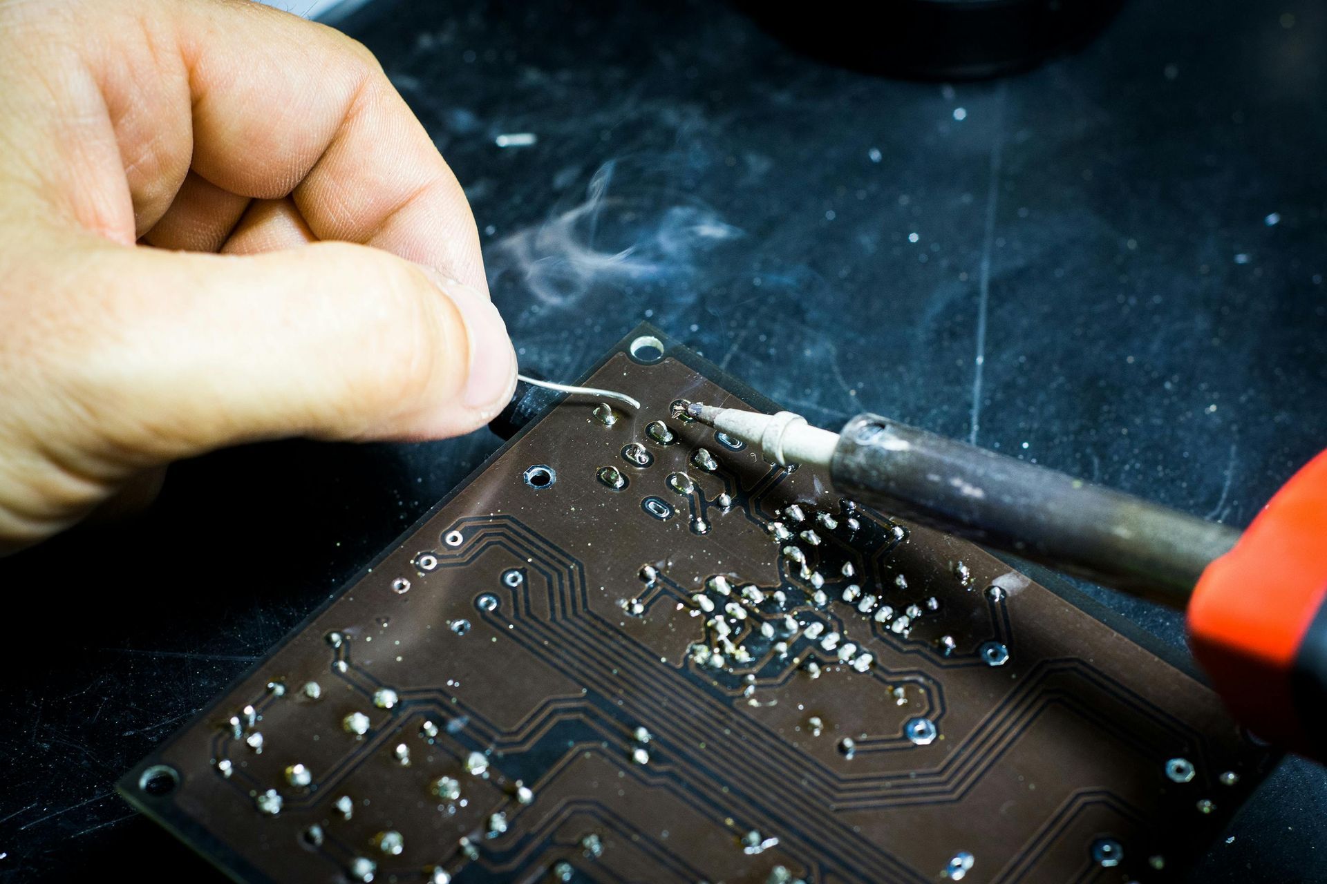 closeup of mans hands soldering a circuit board