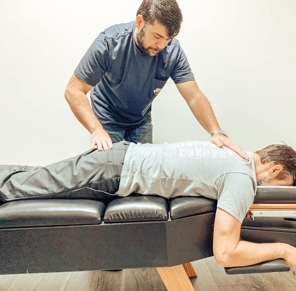 A man is laying on a table getting a massage from another man.