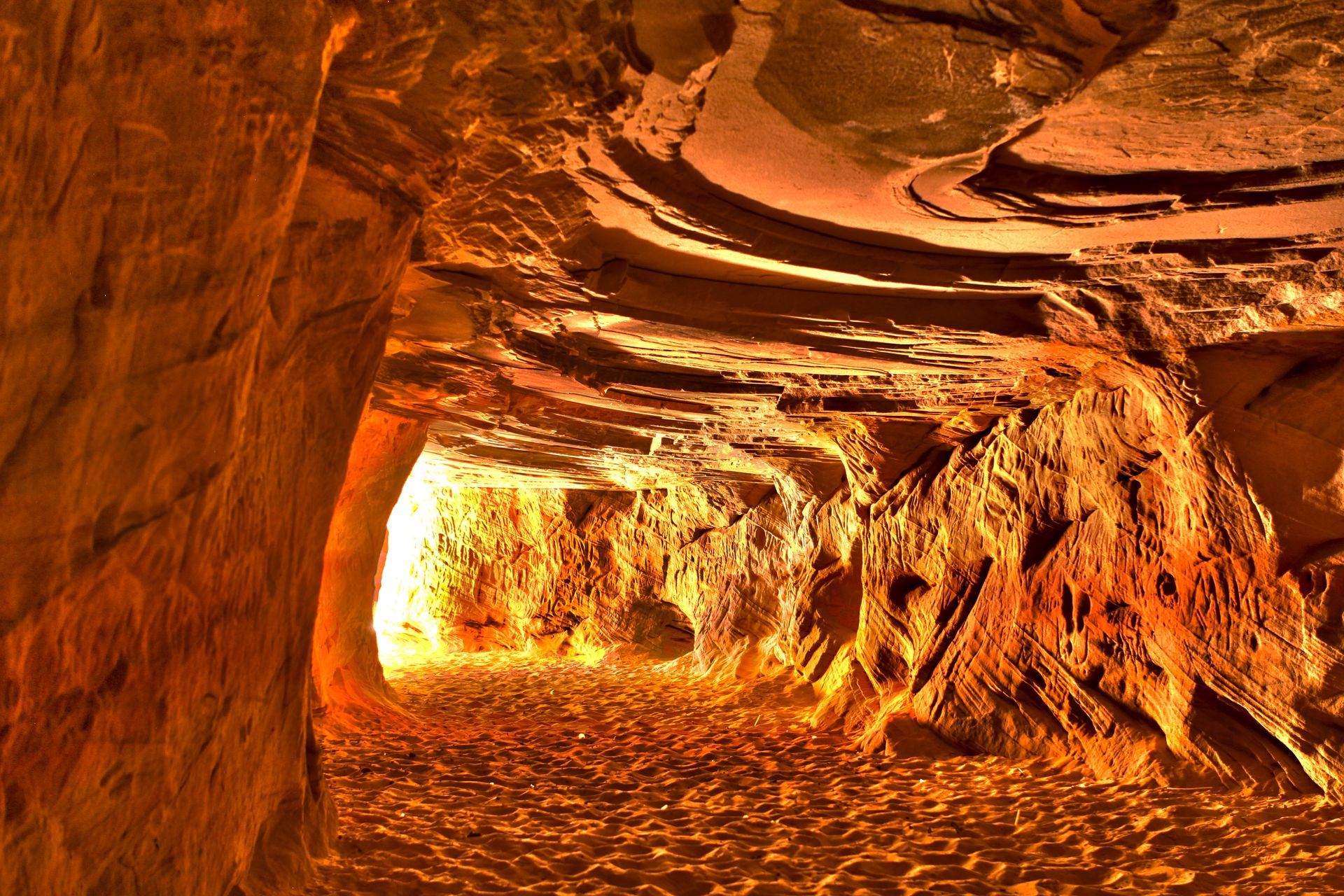 Orange-lit cave tunnel with rocky walls and glowing light at the far end