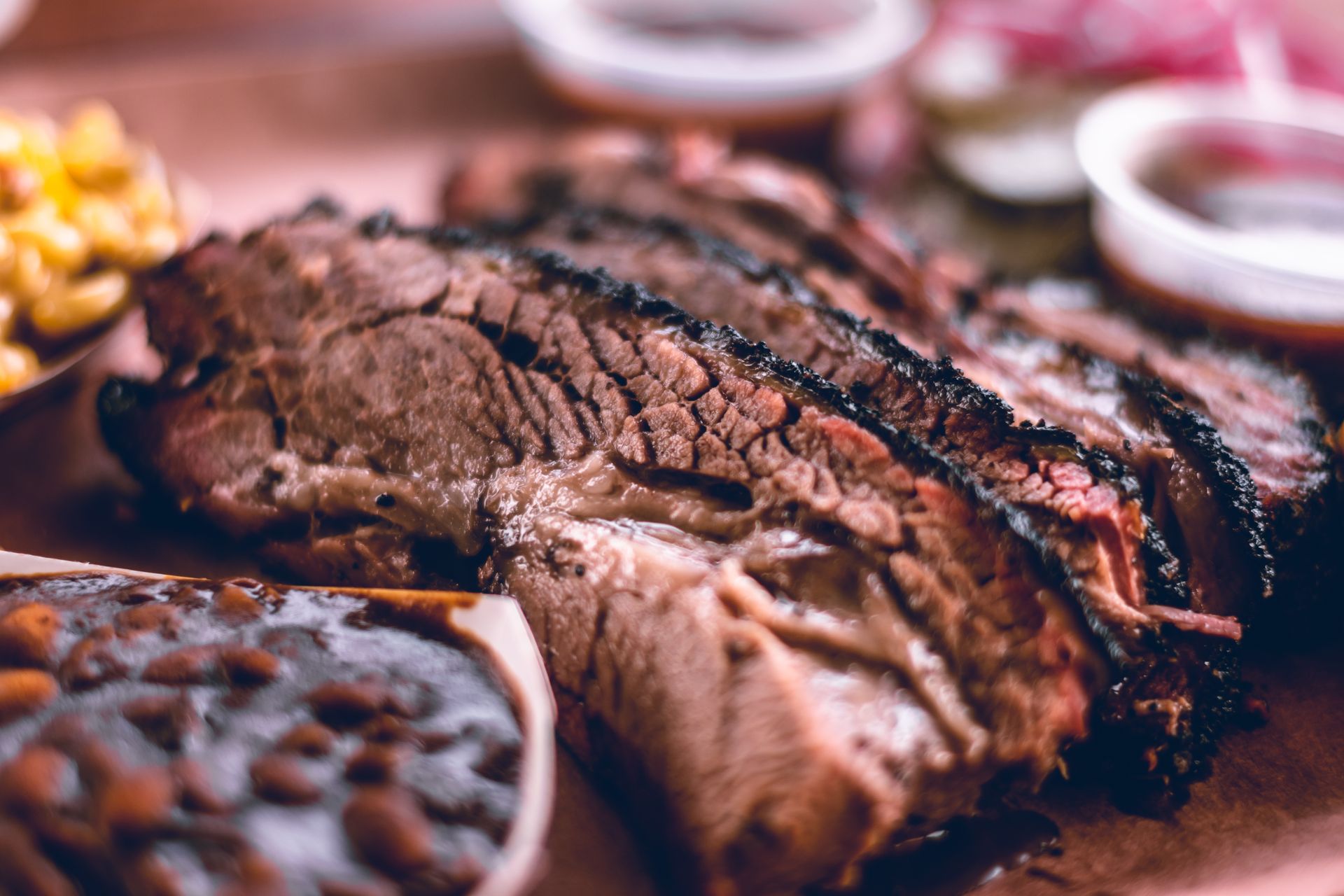 Sliced smoked brisket on a platter, with a dark bark and pink smoke ring