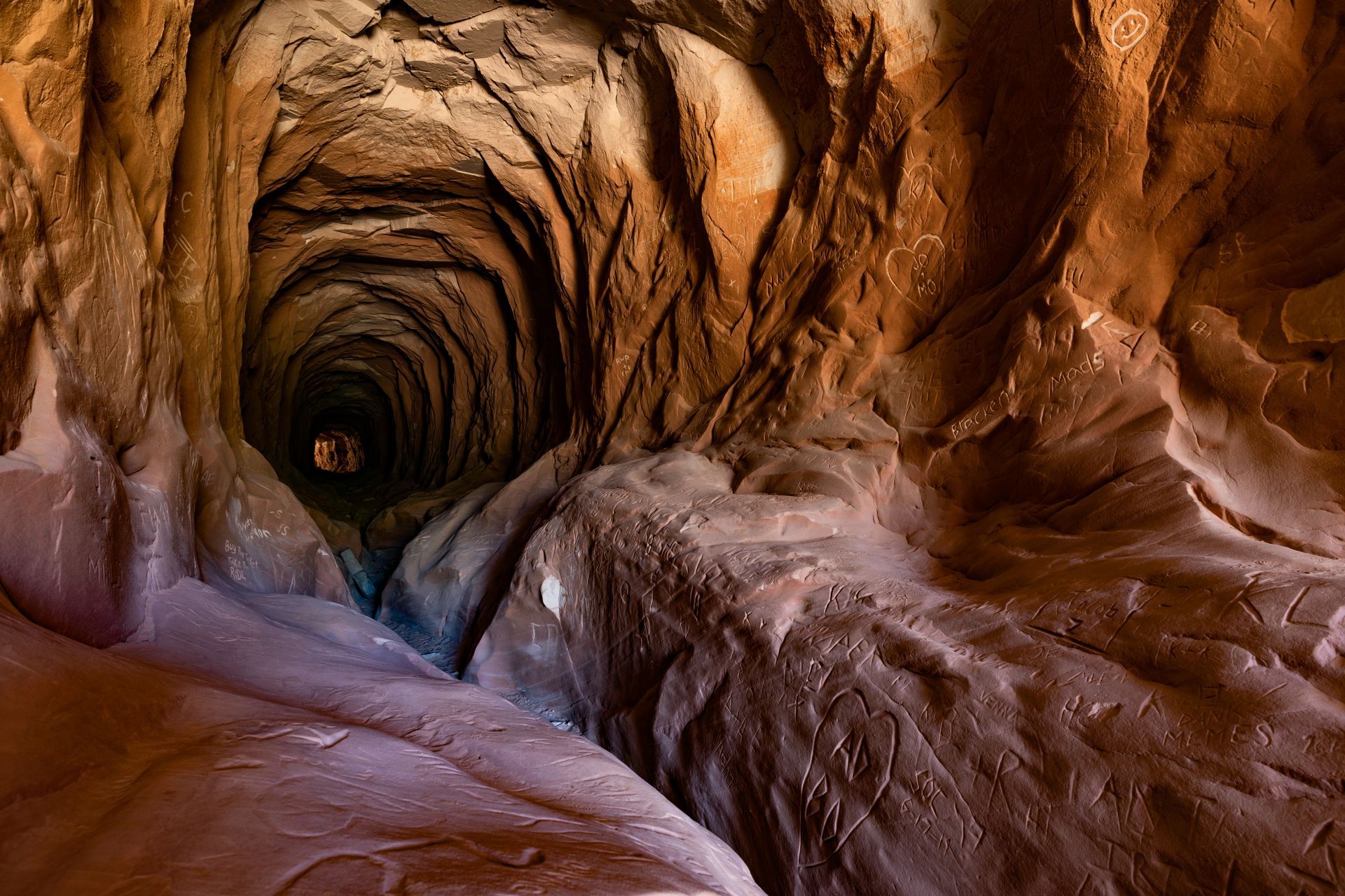 Rocky tunnel interior with a winding, reddish-brown passage fading into darkness