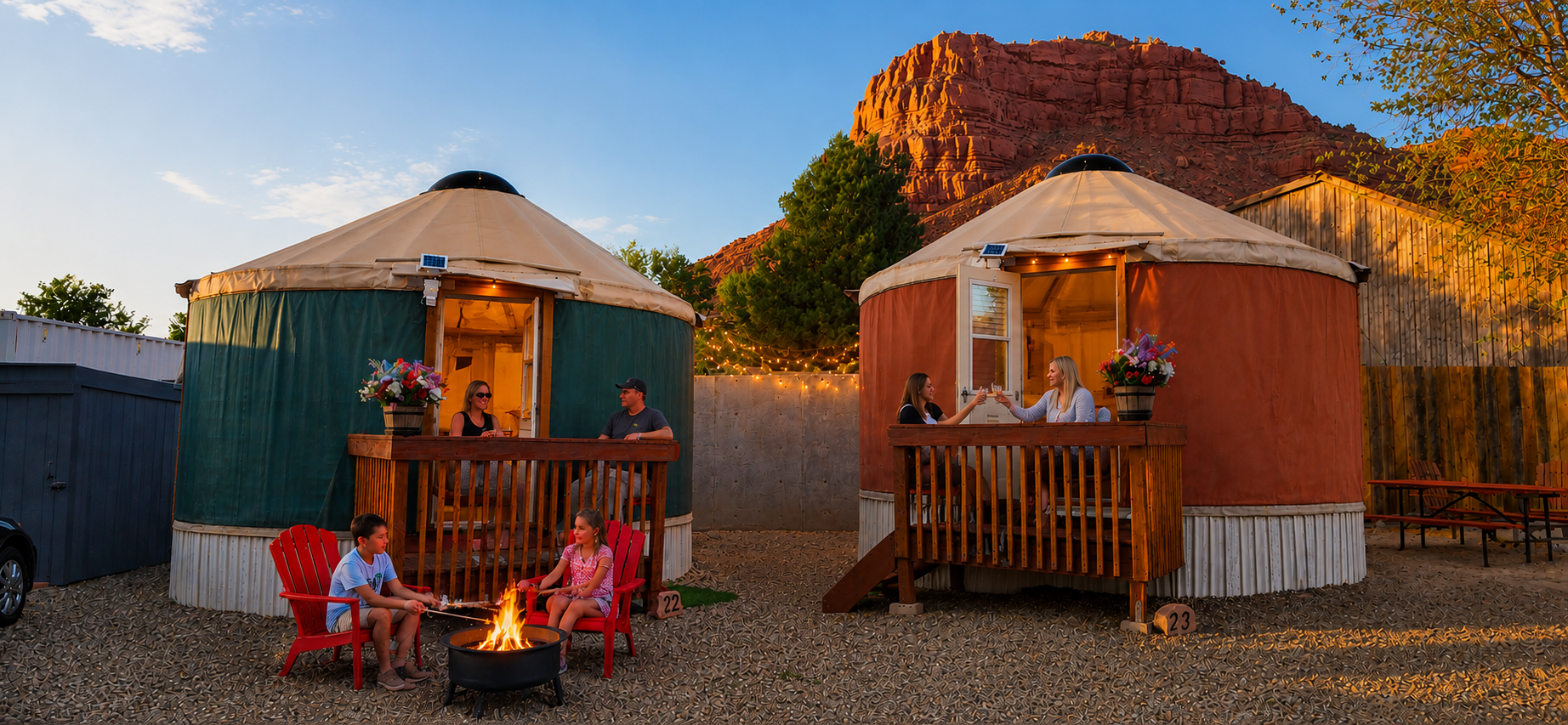 Round yurt cabin with porch in a desert landscape, backed by red sandstone cliffs and trees.