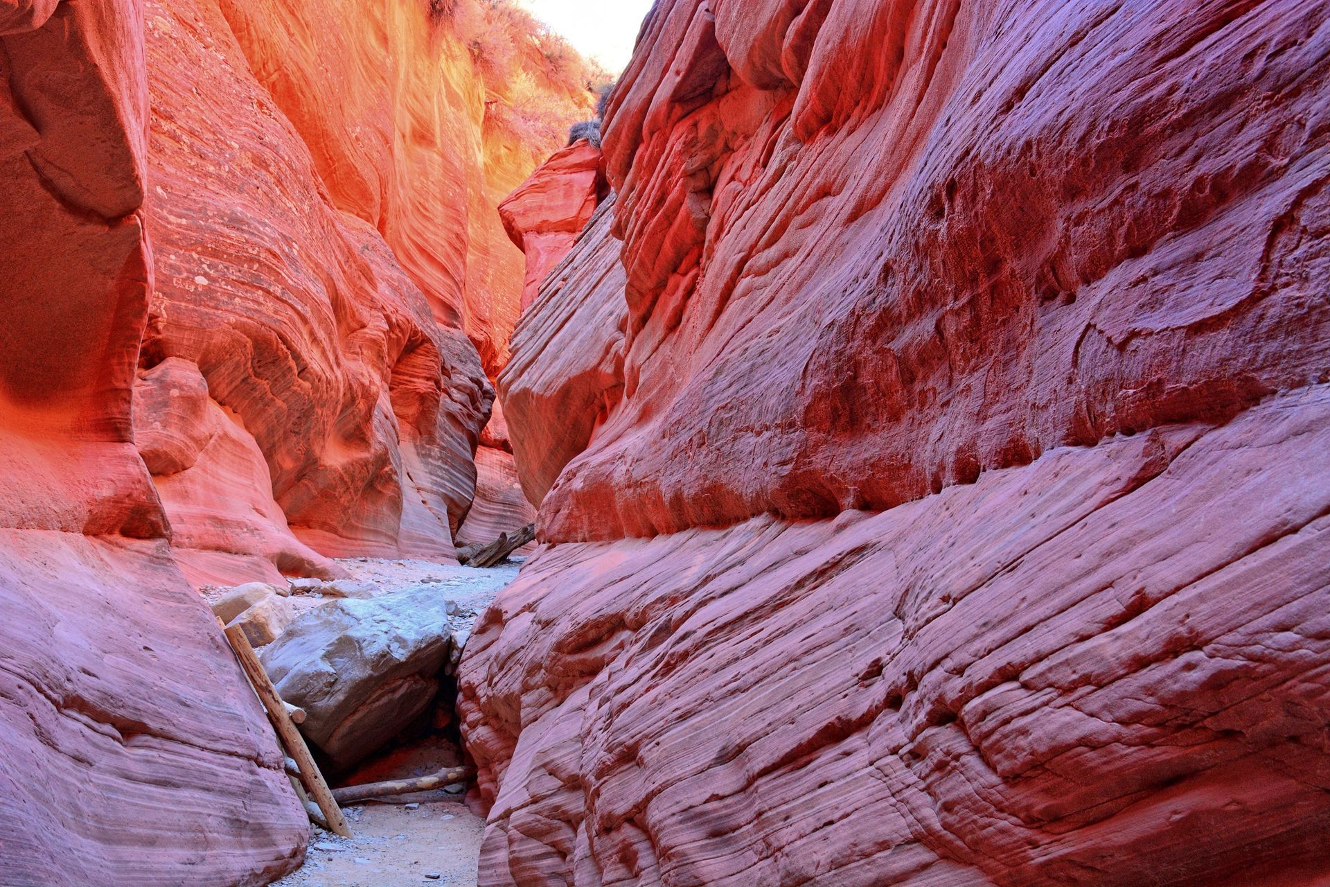 Red sandstone canyon walls framing a narrow rocky path with sunlight above