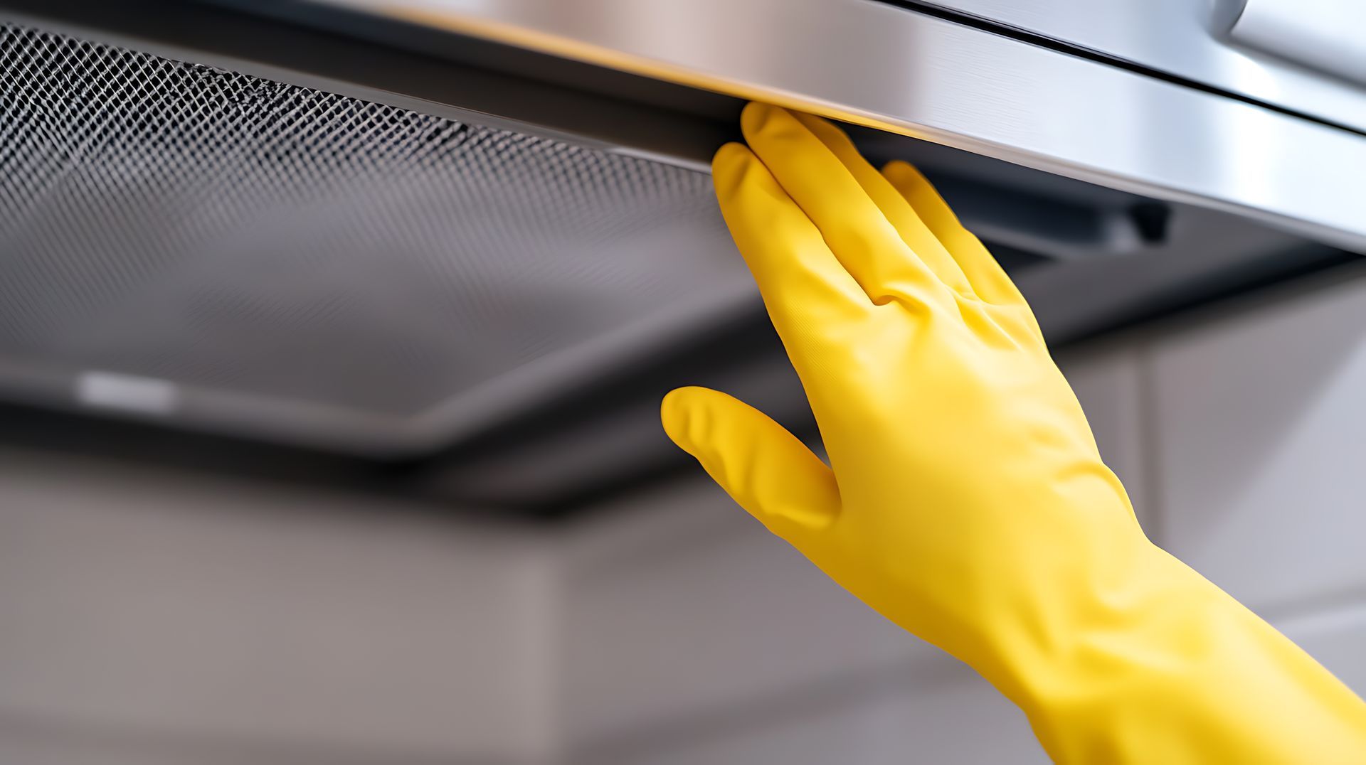 Yellow glove stretches up to change vent hood filter Yellow glove stretches up to change vent hood filter