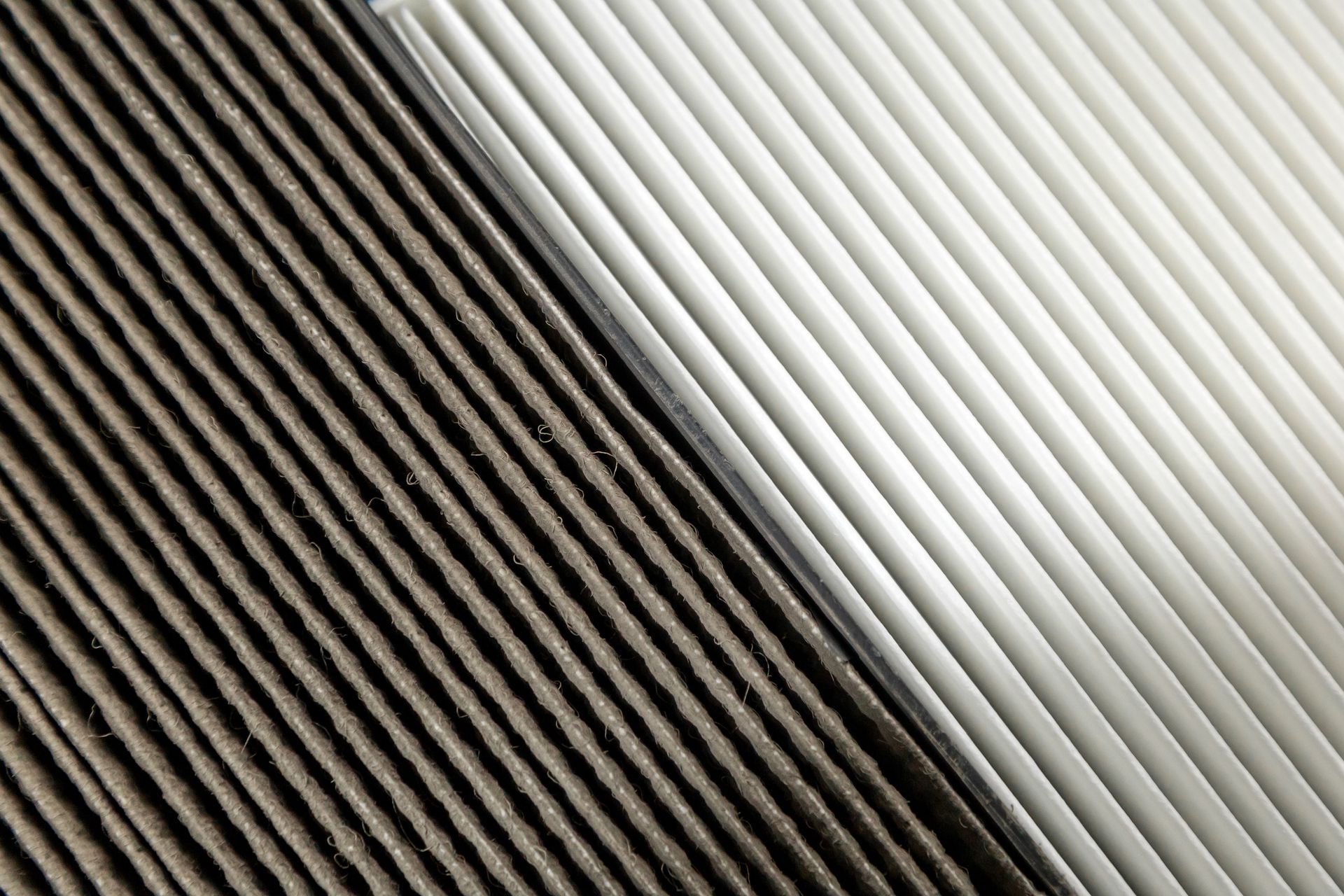 Close-up comparison of dirty and clean pleated air filters side by side.