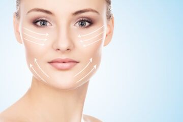 Primo piano del volto di una donna con frecce di contorno bianche sulle guance, che suggeriscono un trattamento cosmetico per la cura della pelle.