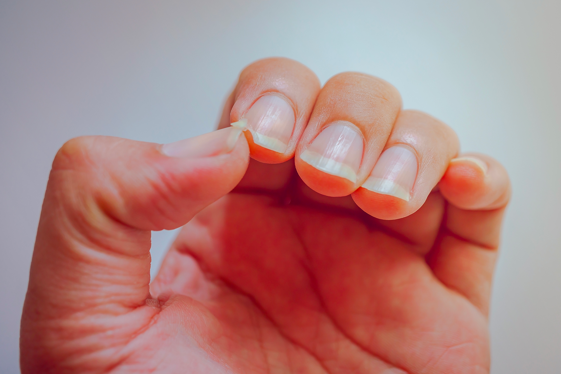 Primo piano di una mano che tiene e stringe tra le dita un piccolo oggetto trasparente.