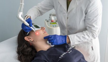 Un dentista visita un paziente sdraiato su una poltrona, utilizzando una lampada e strumenti odontoiatrici in una clinica.