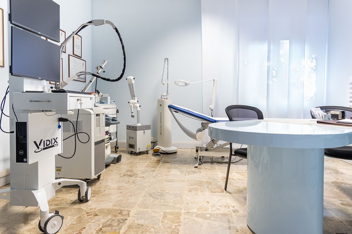 Moderna sala per visite mediche con apparecchiatura a raggi X, poltrona reclinabile e tavolo circolare.