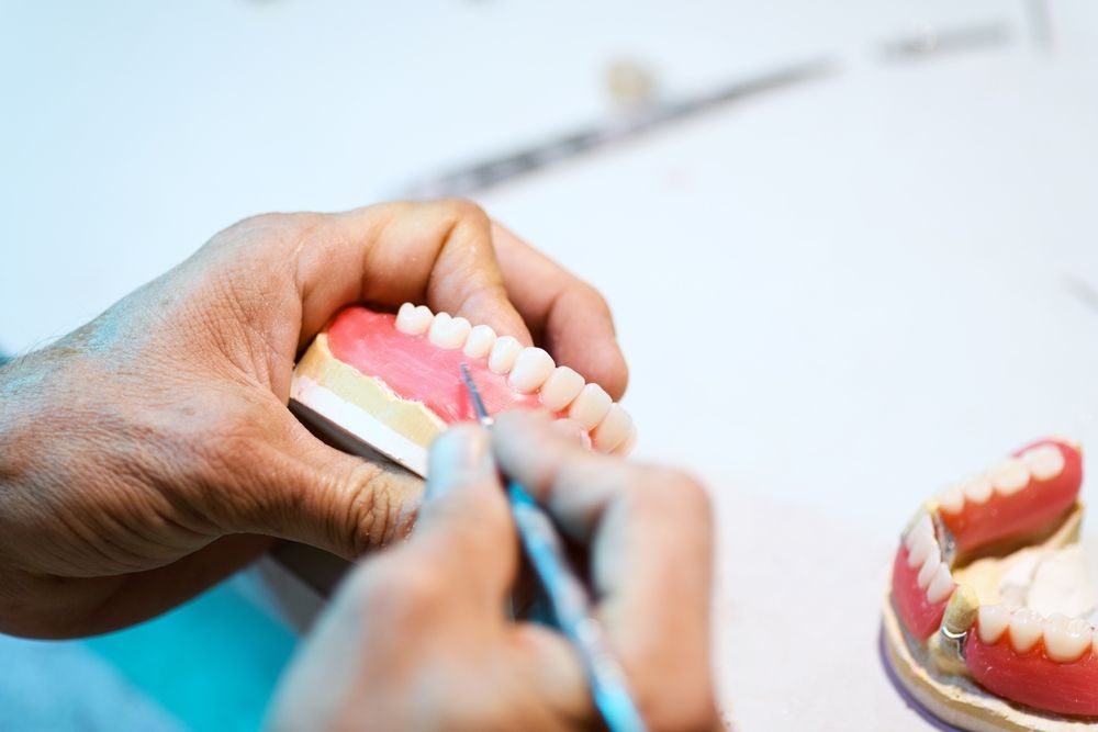 A Dentist is Working on a Model of a Person's Teeth — Goonellabah Denture Clinic in Brunswick Heads, NSW