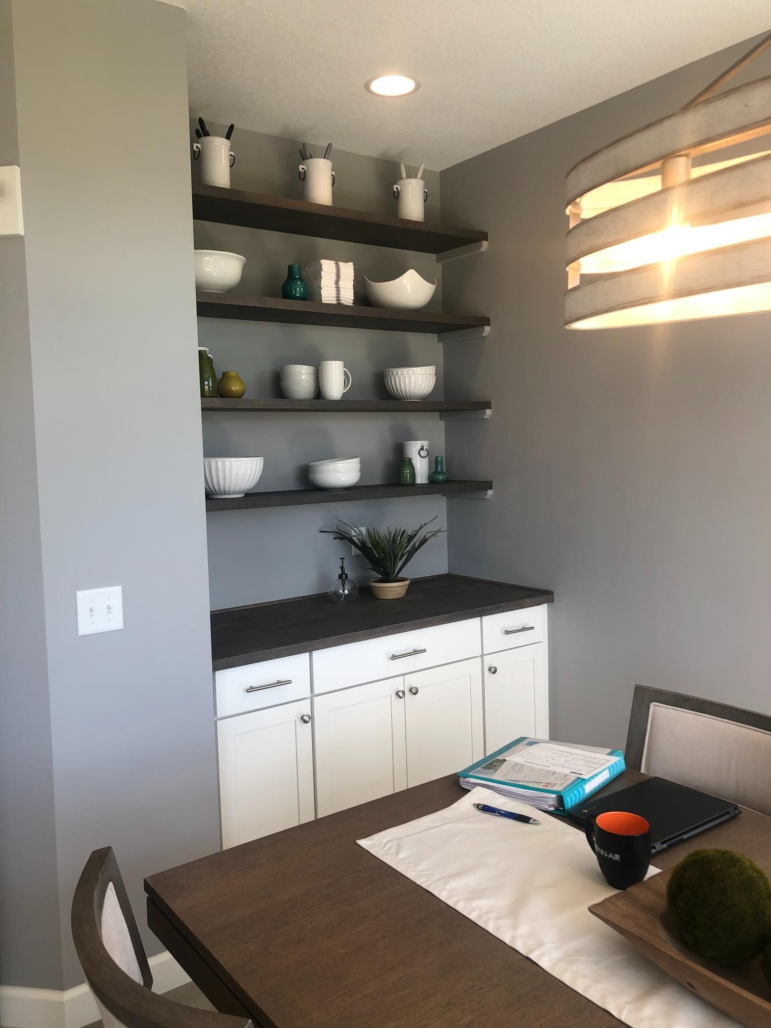 A dining room with a table and shelves filled with bowls