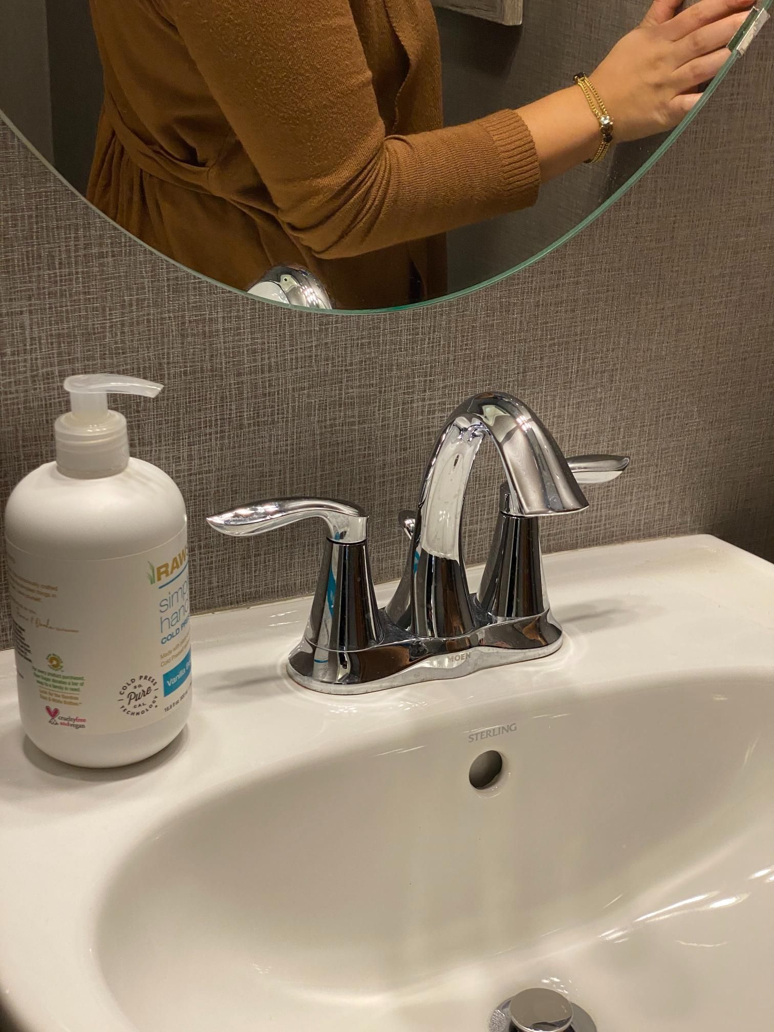A woman is brushing her teeth in a bathroom sink.