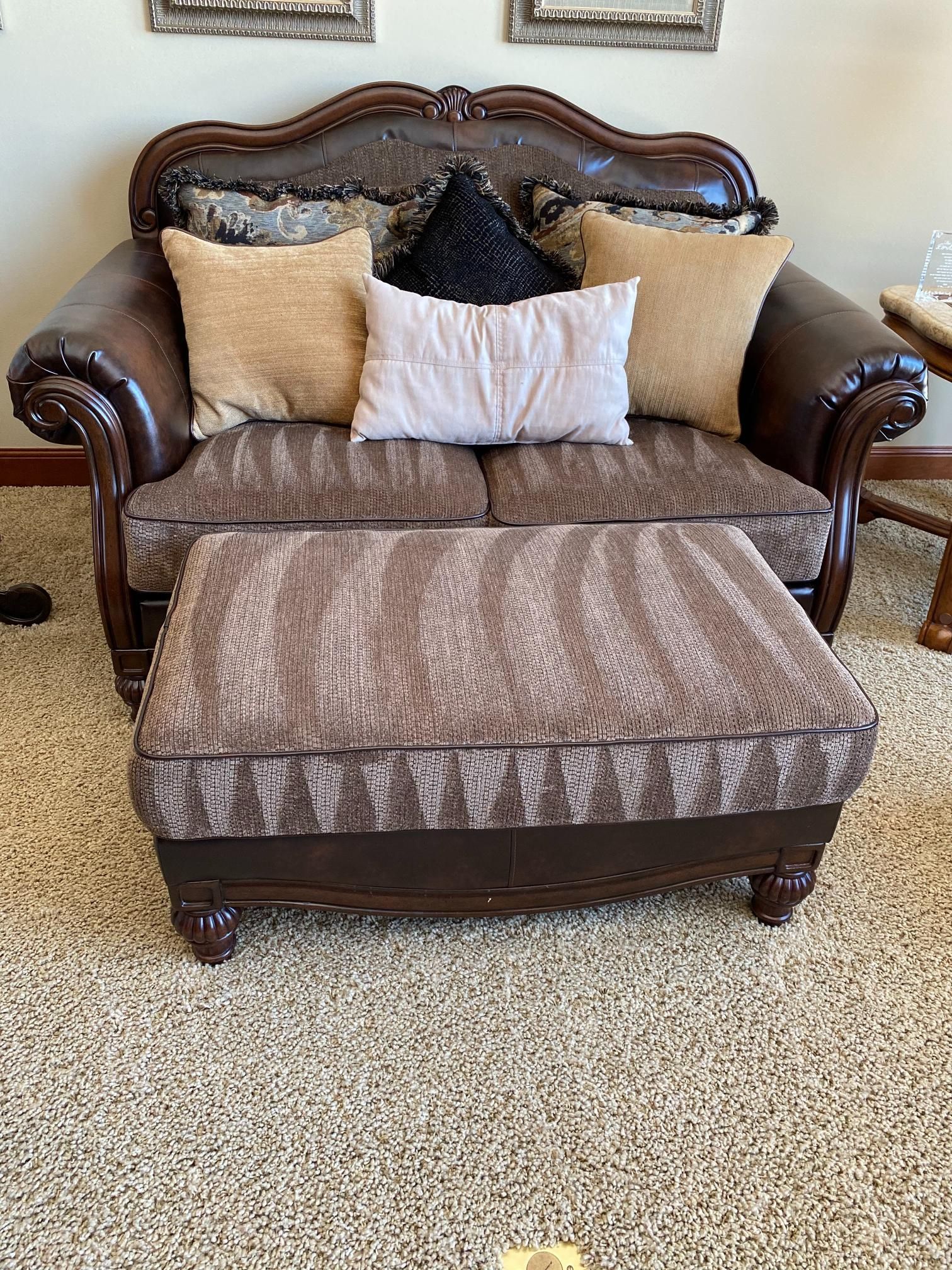 A living room with a couch , chair and ottoman.