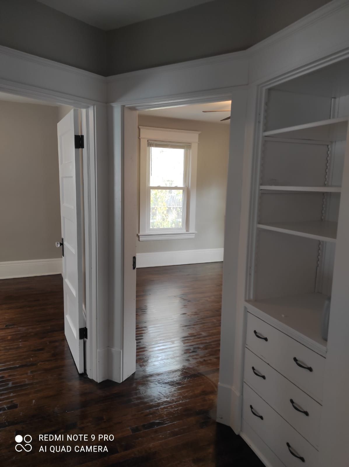 A corner of a room with a window and shelves.