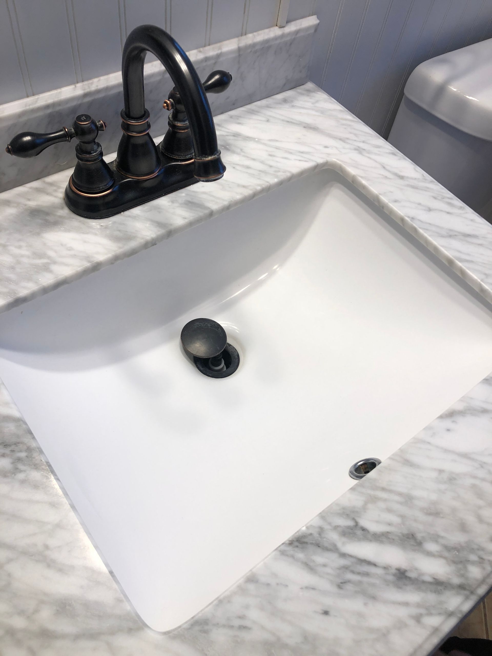 A bathroom sink with a black faucet on a marble counter top.