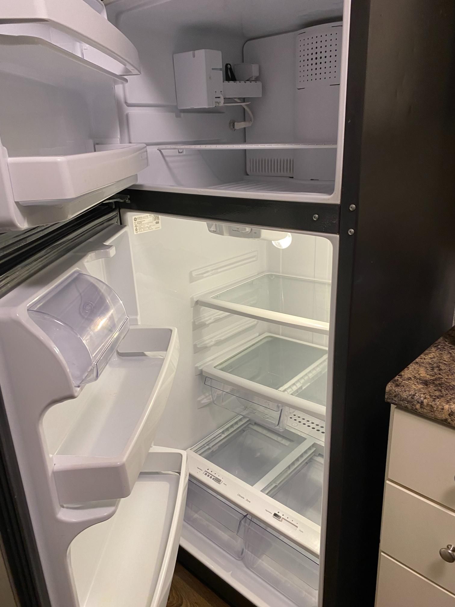 An empty refrigerator with the door open in a kitchen.