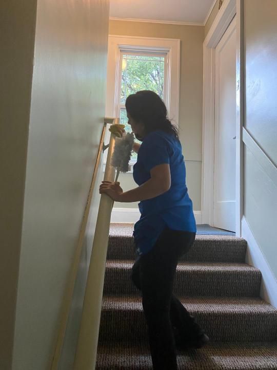 A woman is cleaning a railing on a set of stairs.