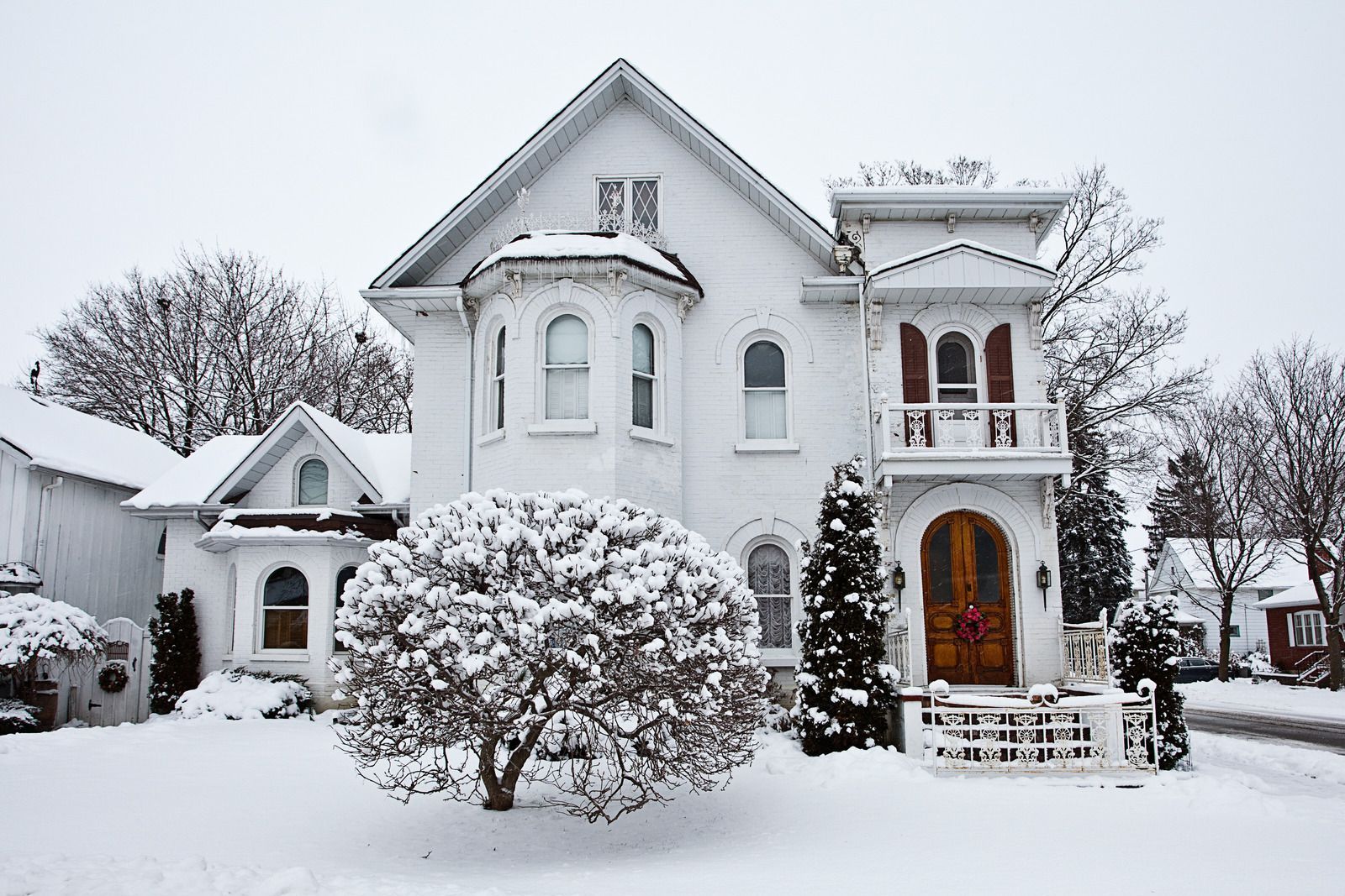 A large white house is covered in snow.