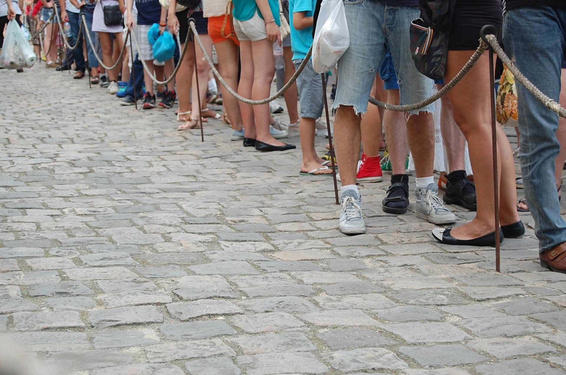A group of people are standing in a line on a cobblestone street.