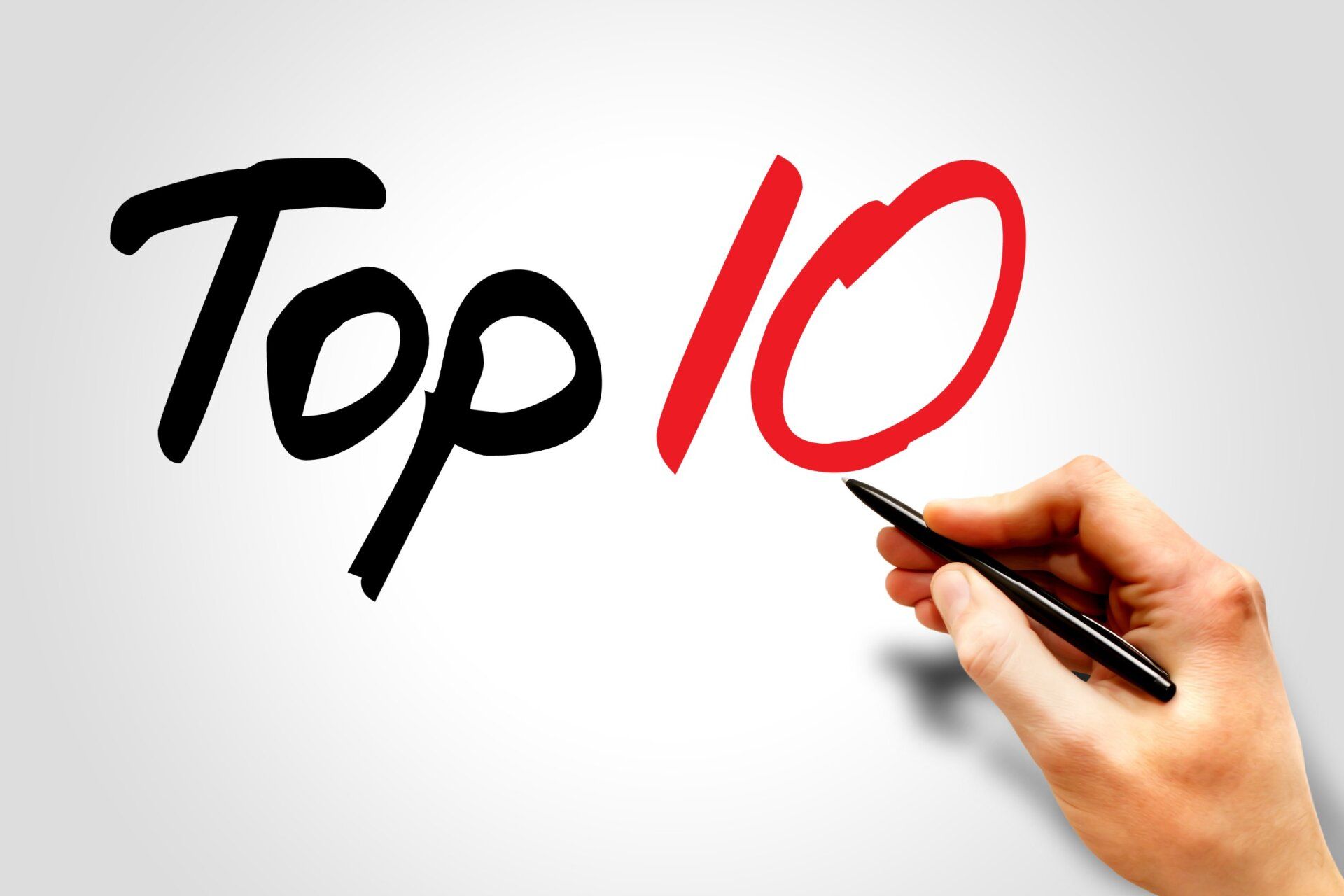 A hand is writing the word top 10 with a pen