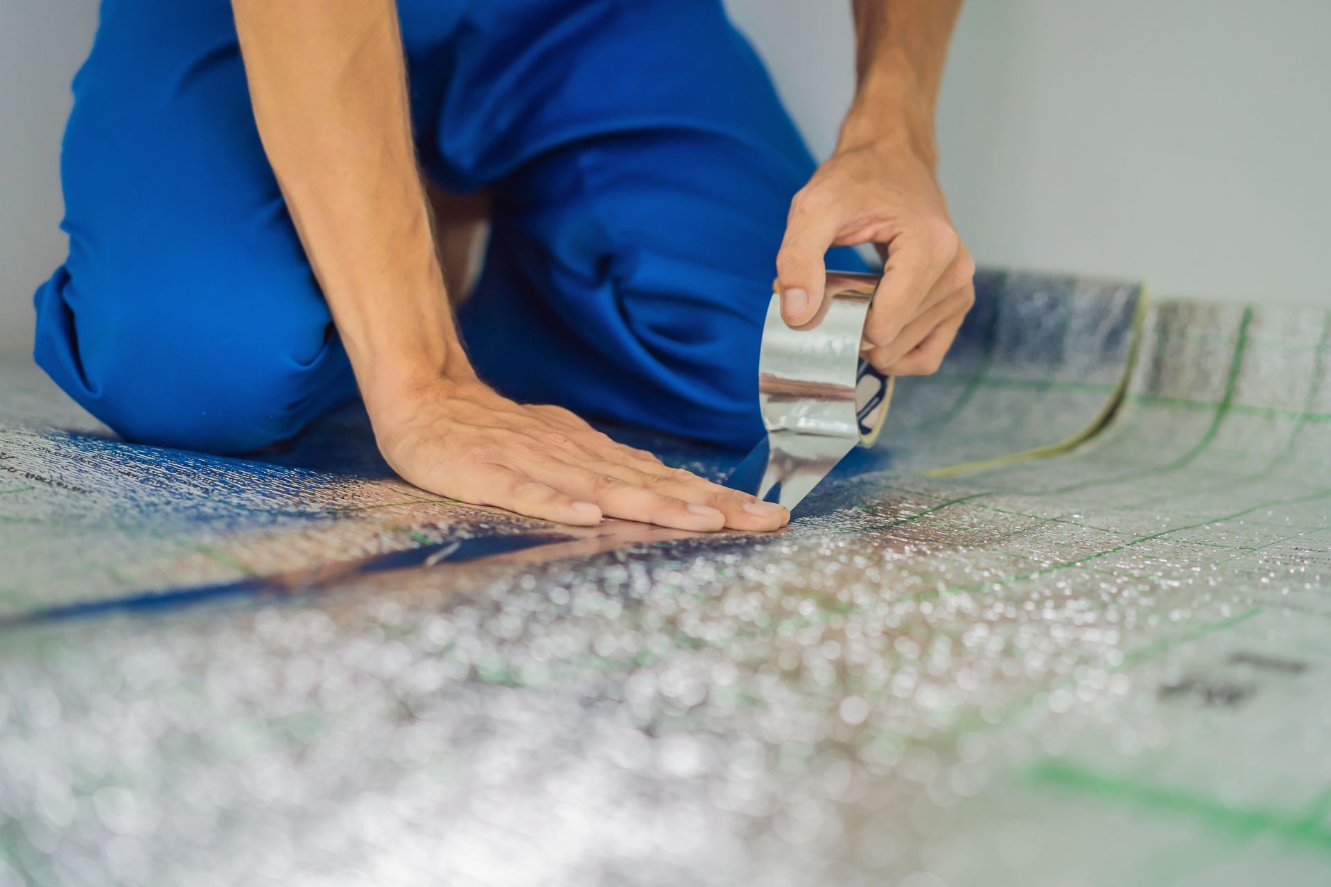 A man is kneeling down and cutting a piece of duct tape.