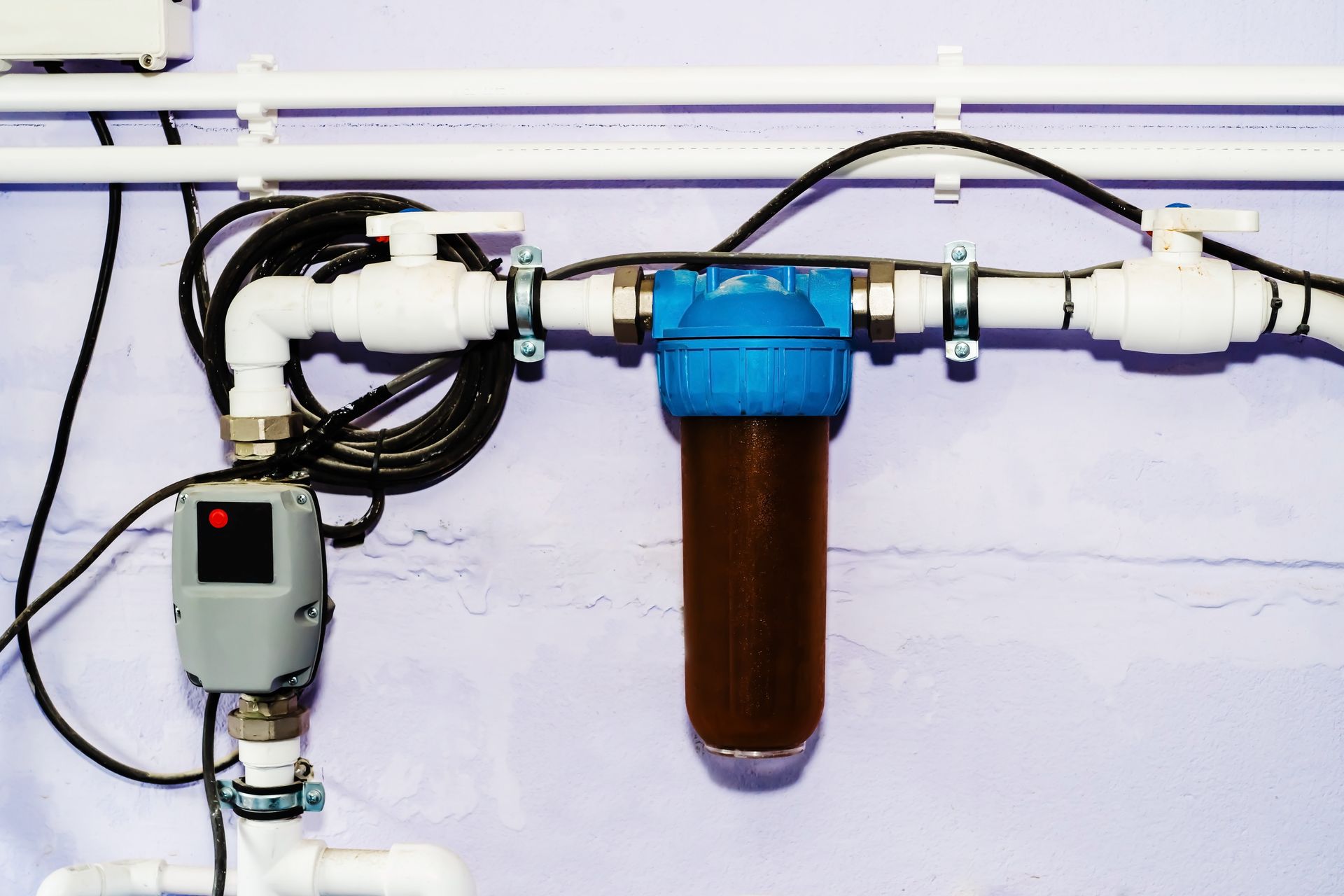 A water filter is attached to a pipe on a wall.