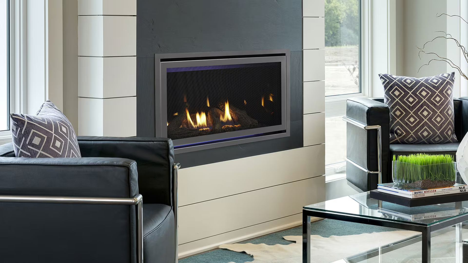 Modern living room with a fireplace and black leather chairs.