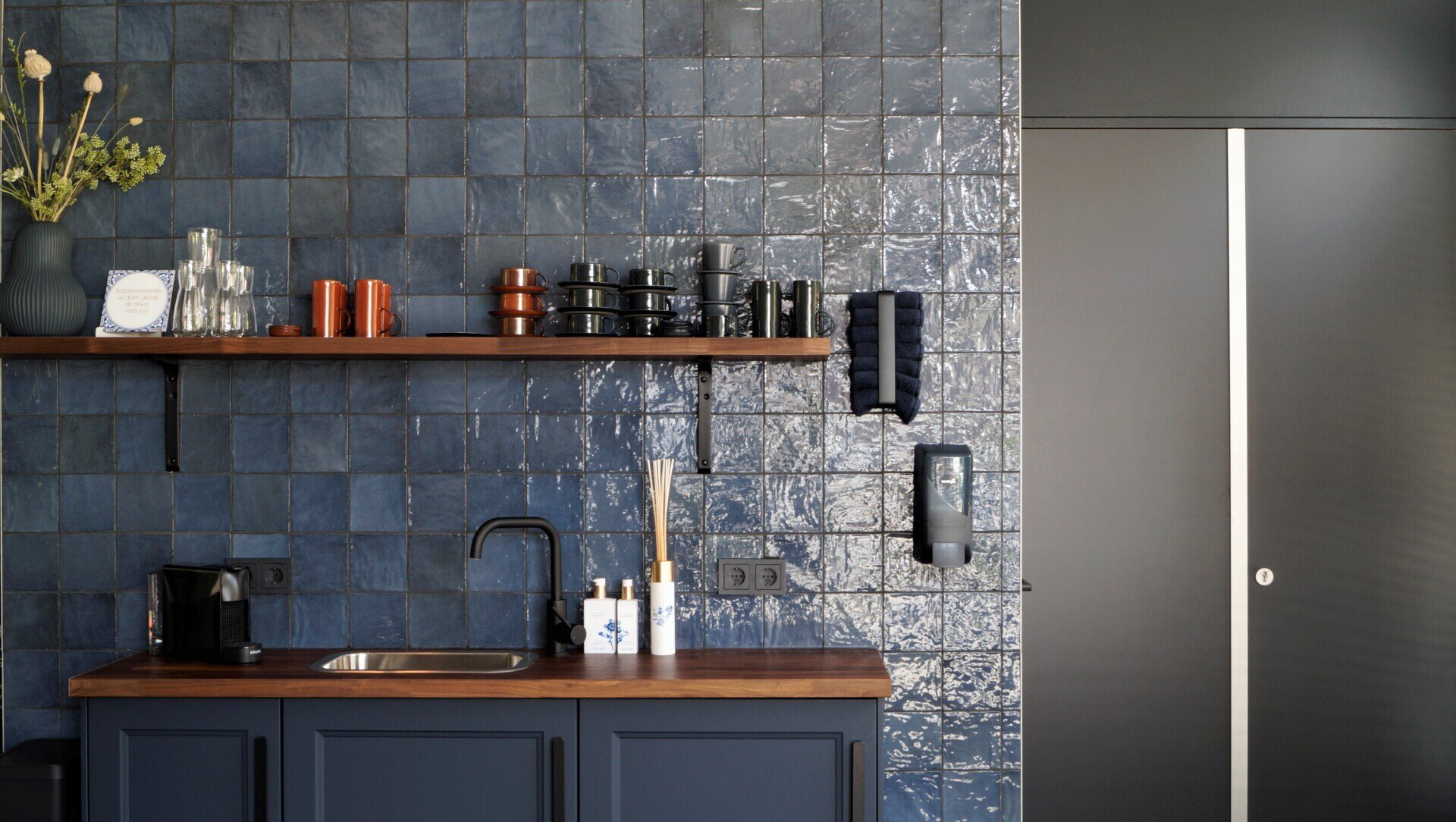 Blauwe handgevormde wandtegels over de hele wand.